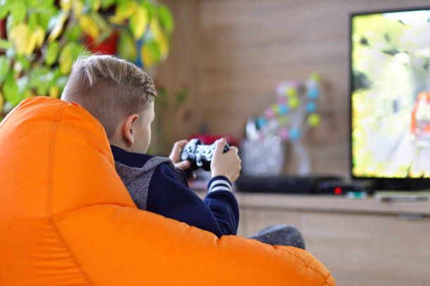 Young gamer boy playing online game on new console at home tv - little kid addicted to technology